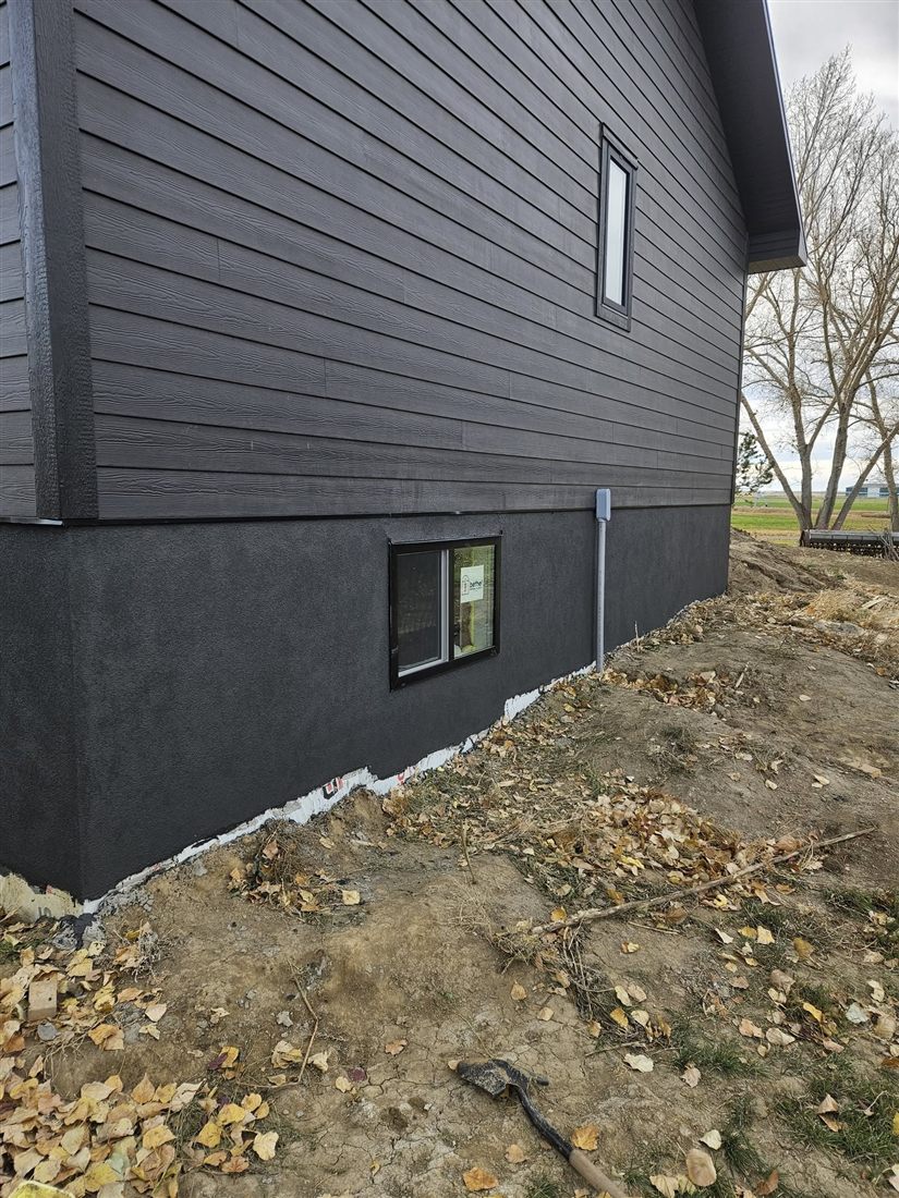 A crisp single line where True North's charcoal parging meets the siding