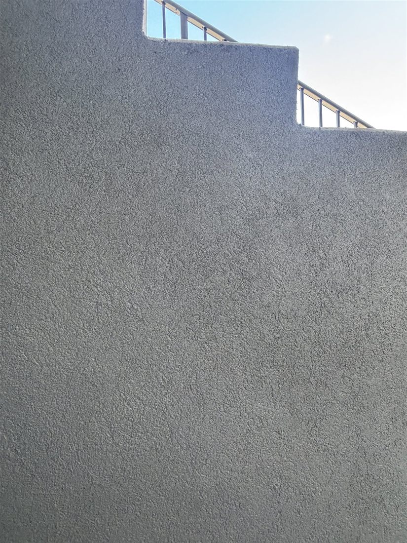 Smooth grey parging with a clean line where it meets the siding