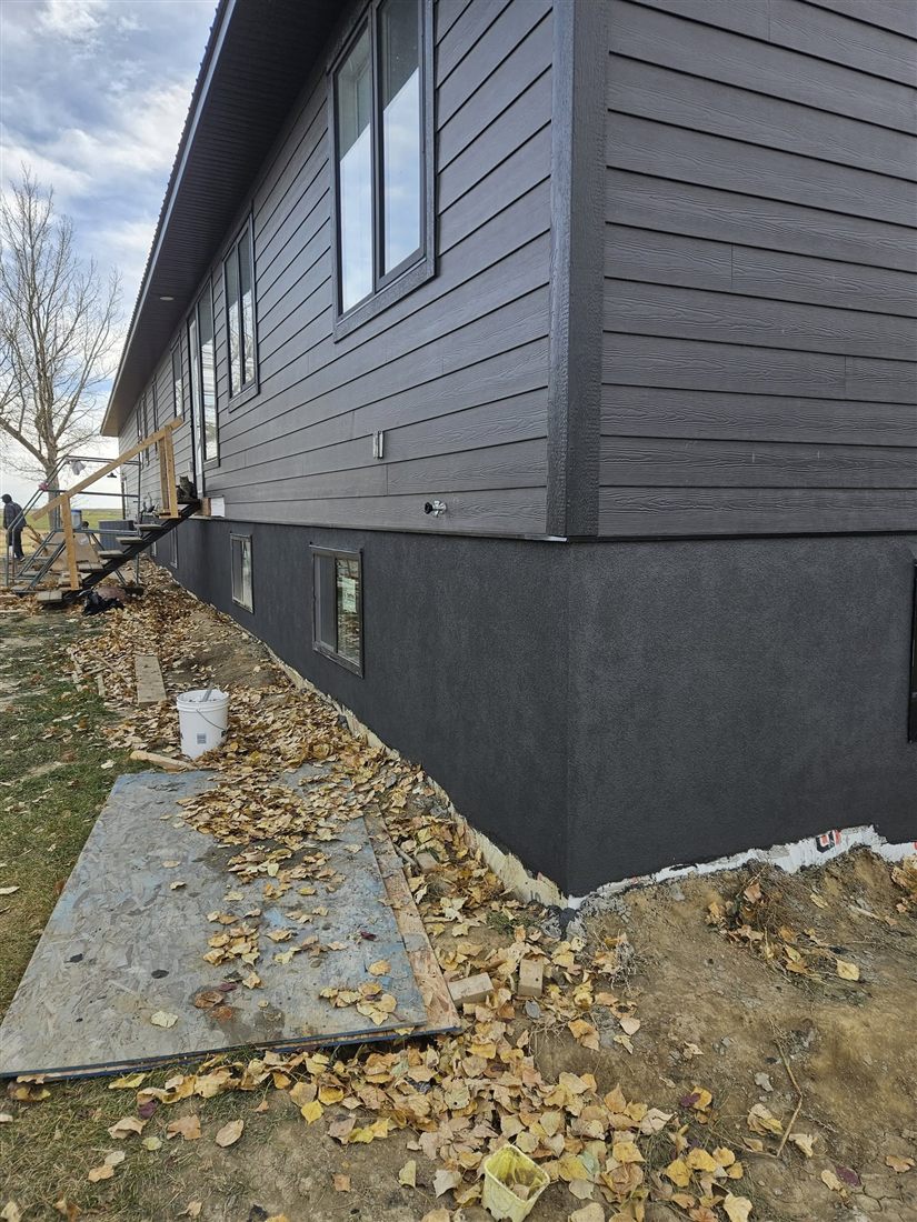 Charcoal parged foundation corner on a dark-sided home
